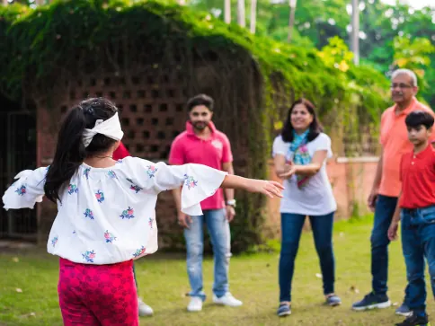 Jeu en famille dans un jardin : une enfant aux yeux bandés cherche les autres joueurs