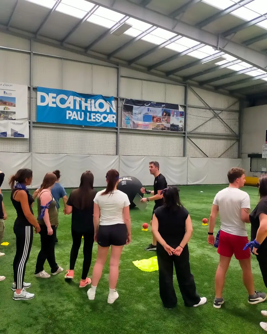 Participants réunis en cercle avant une épreuve, en salle indoor